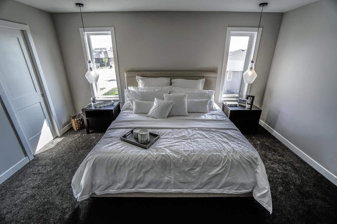 Chambre moderne lumineuse avec un grand lit double blanc prêt à accueillir une moustiquaire lit pour des nuits paisibles