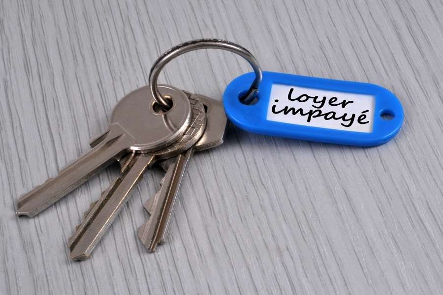 Un trousseau de clés avec une étiquette bleue indiquant "loyer impayé", illustrant les risques liés aux retards de paiement de loyer.