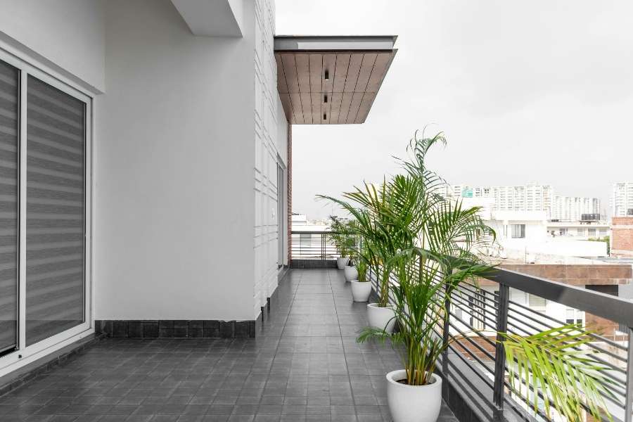 Un long balcon moderne avec des pots de plantes vertes pour se protéger des regards.